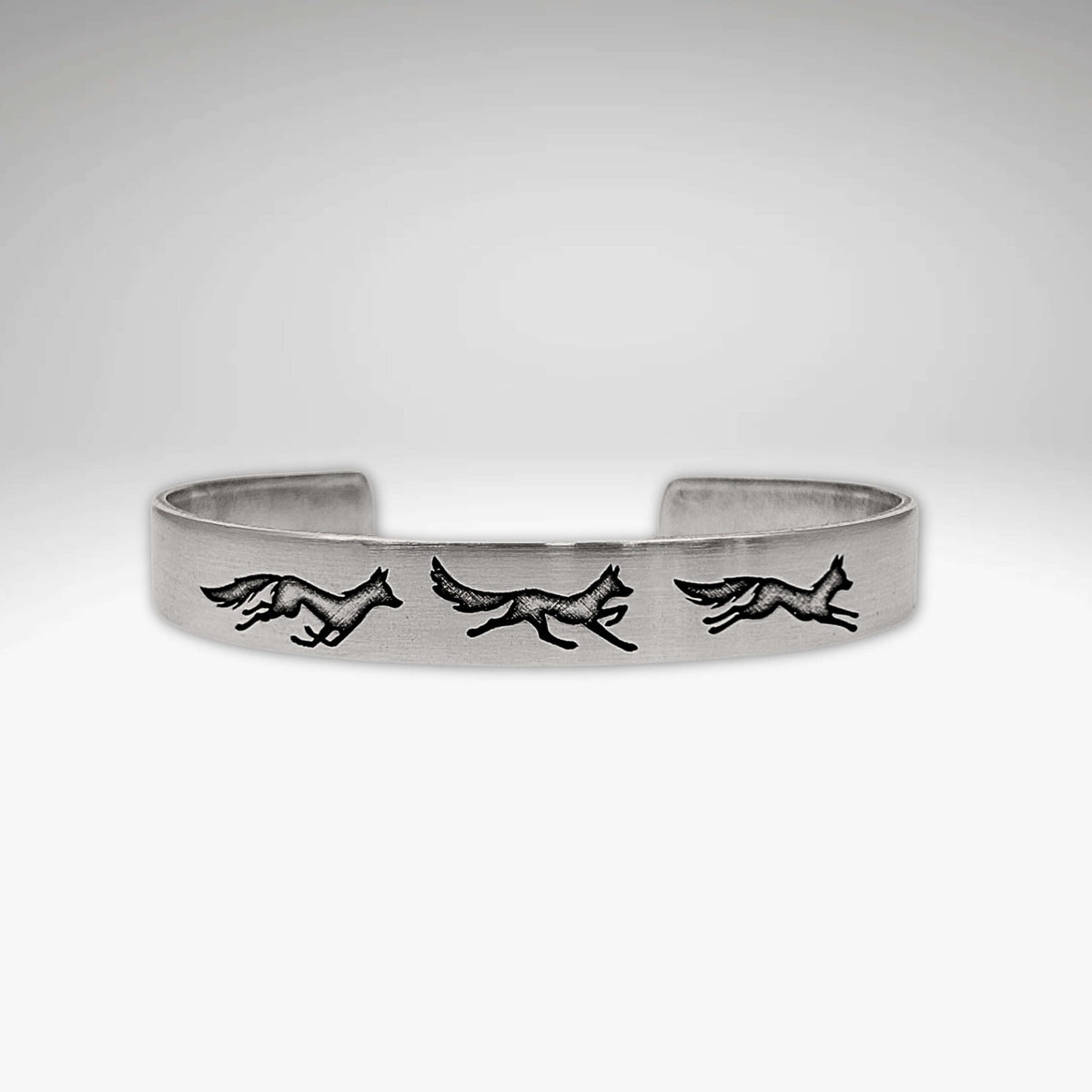 Fox Run Cuff Bracelet showcasing three playful foxes on a matte silver cuff.