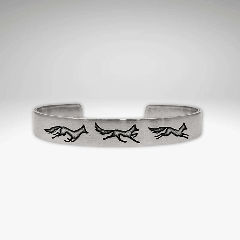 Fox Run Cuff Bracelet showcasing three playful foxes on a matte silver cuff.
