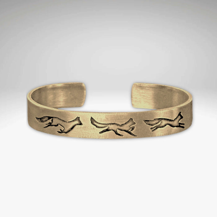 Antique brass Fox Run Cuff Bracelet featuring three running foxes, perfect for adding wilderness charm to any outfit.