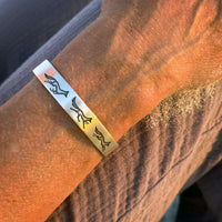 Fox Run Cuff Bracelet in matte silver on a wrist, featuring three running foxes in a whimsical chase.