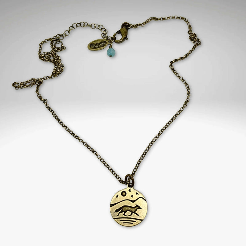 Fox Run Necklace featuring a handmade pendant of a fox running under a night sky on an antique brass chain.
