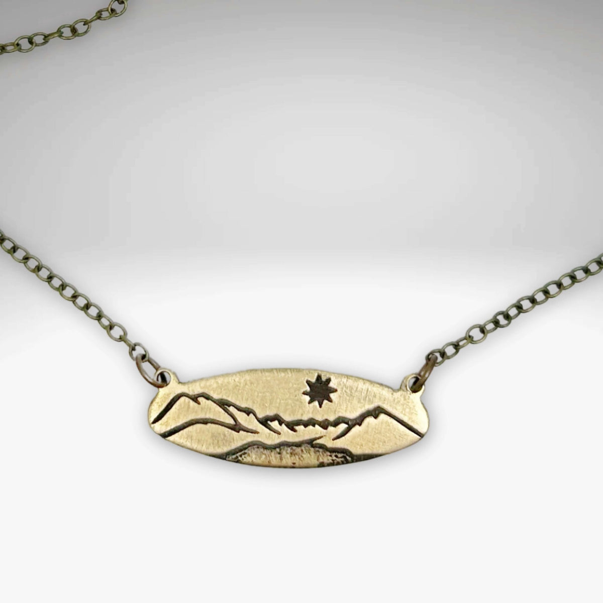 Glacier View Necklace in antique brass finish with mountain design pendant on adjustable cable chain.