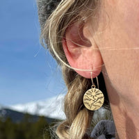Going to the Sun Earrings worn by a woman outdoors, highlighting the nature-inspired design against a scenic background.