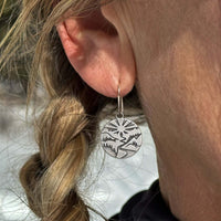 Person wearing Going to the Sun Earrings showcasing nature-inspired design in a matte silver finish.