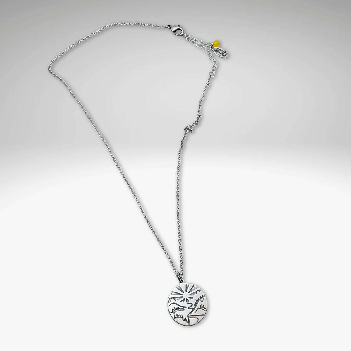 Going to the Sun Necklace featuring a mountain pendant on an adjustable silver chain.