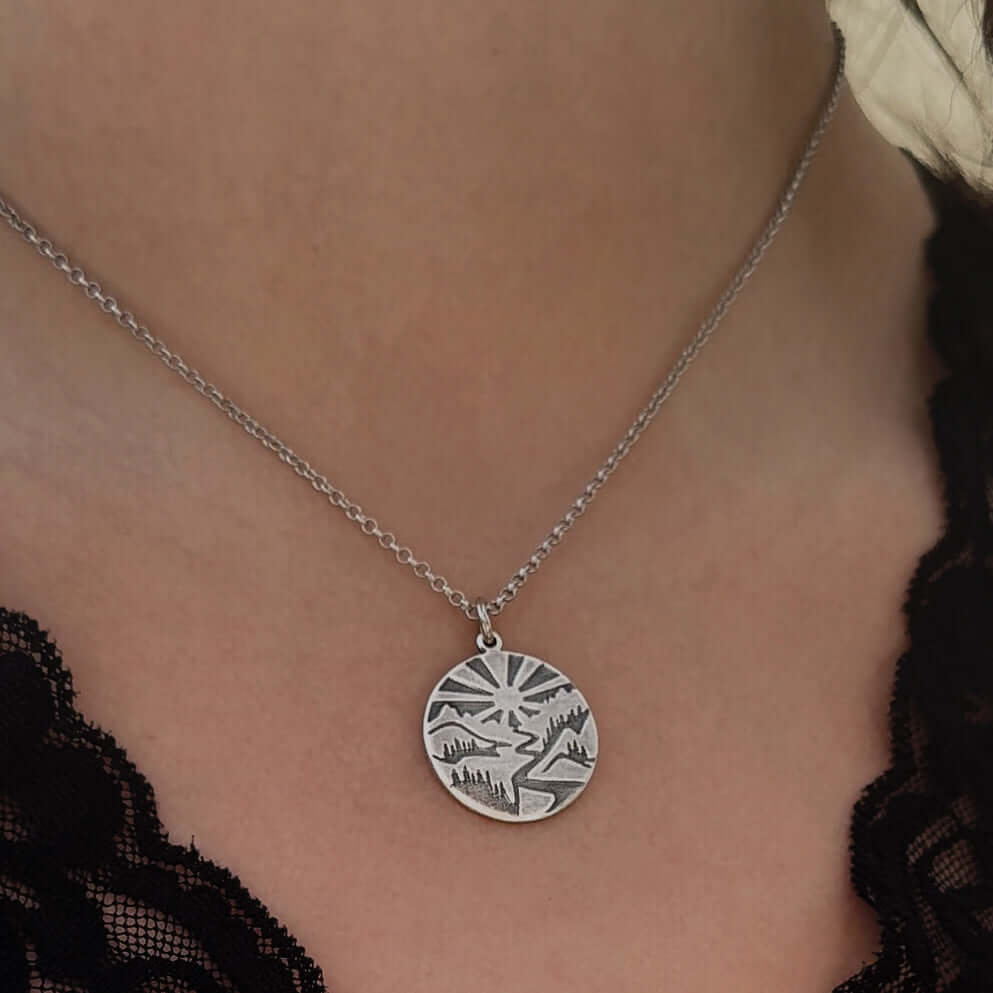 Going to the Sun Necklace featuring a detailed mountain pendant worn on a silver chain.