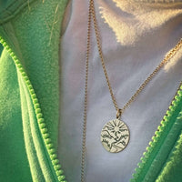 Going to the Sun Necklace worn with a green outfit, showcasing detailed mountain pendant design.
