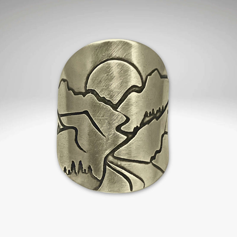 Going to the Sun Road Adjustable Ring featuring etched mountains and sun design in raw brass finish.