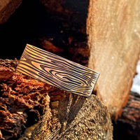 Grain Cuff Bracelet designed to resemble wood fibers against rustic wood background.