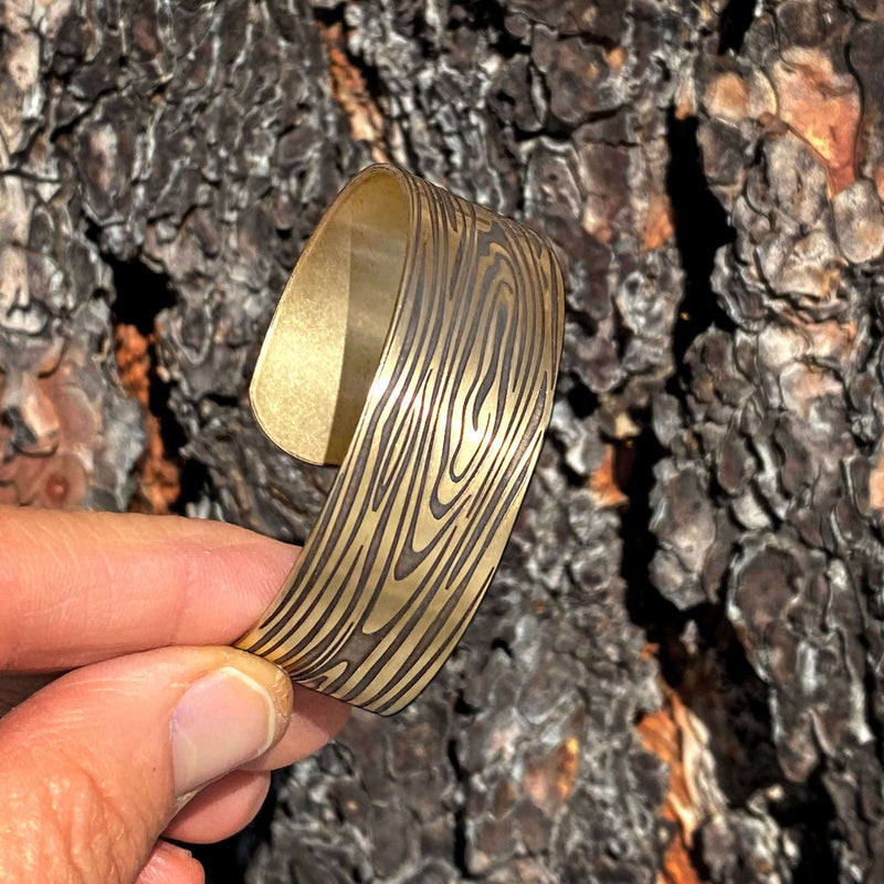 Grain Cuff Bracelet held in hand against textured bark background, showcasing wood-like fiber design.