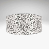 Grand Cuff in matte silver finish featuring intricate topographic design, adjustable and handmade in Montana.