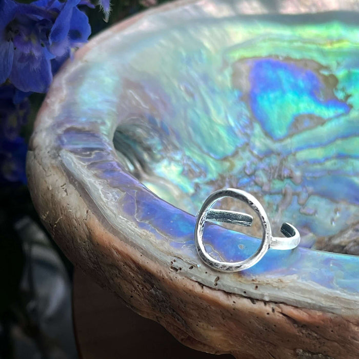 Close-up of Halo Adjustable Ring set on an iridescent shell, showcasing its unique design and texture.