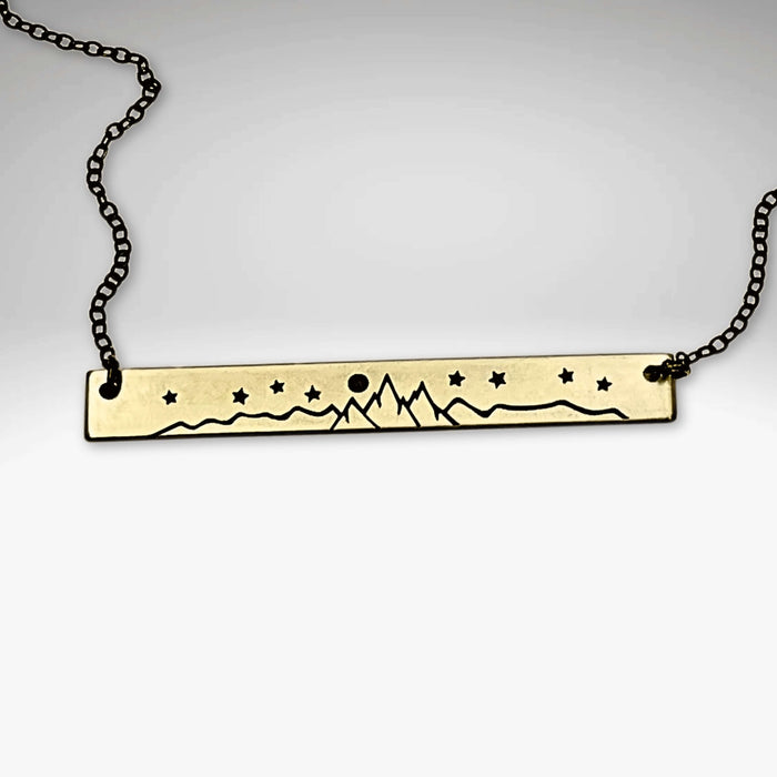 High Alpine Necklace displayed on a chain, featuring a brass pendant with mountain and star etching.
