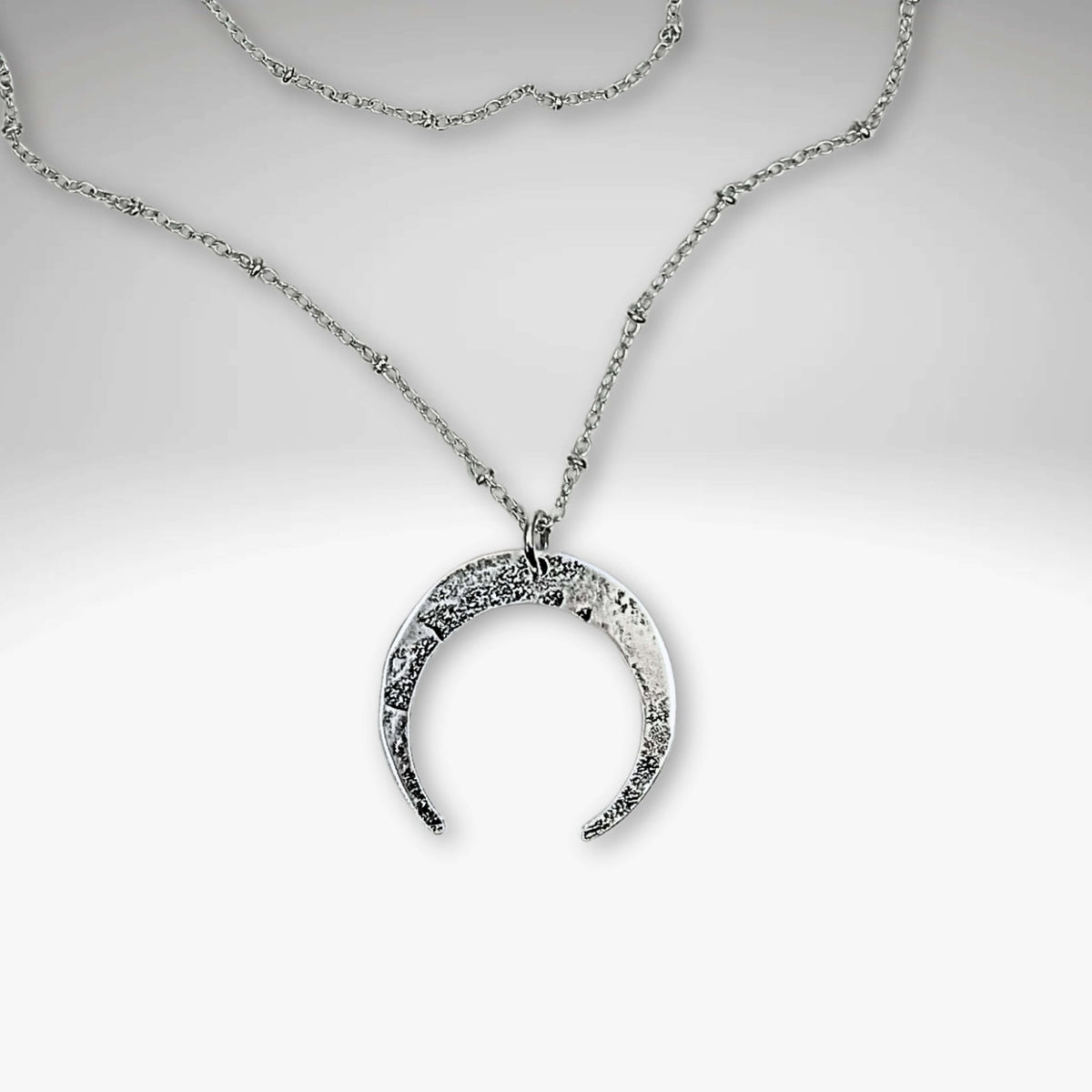 Horned Moon Necklace on satellite chain, featuring a silver pendant and delicate chain, beautifully layered for elegance.