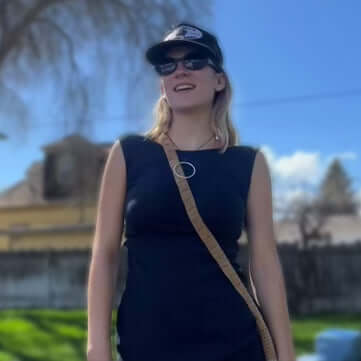 Hula Necklace model wearing a stylish outfit with a cap and sunglasses, showcasing a vibrant outdoor setting.