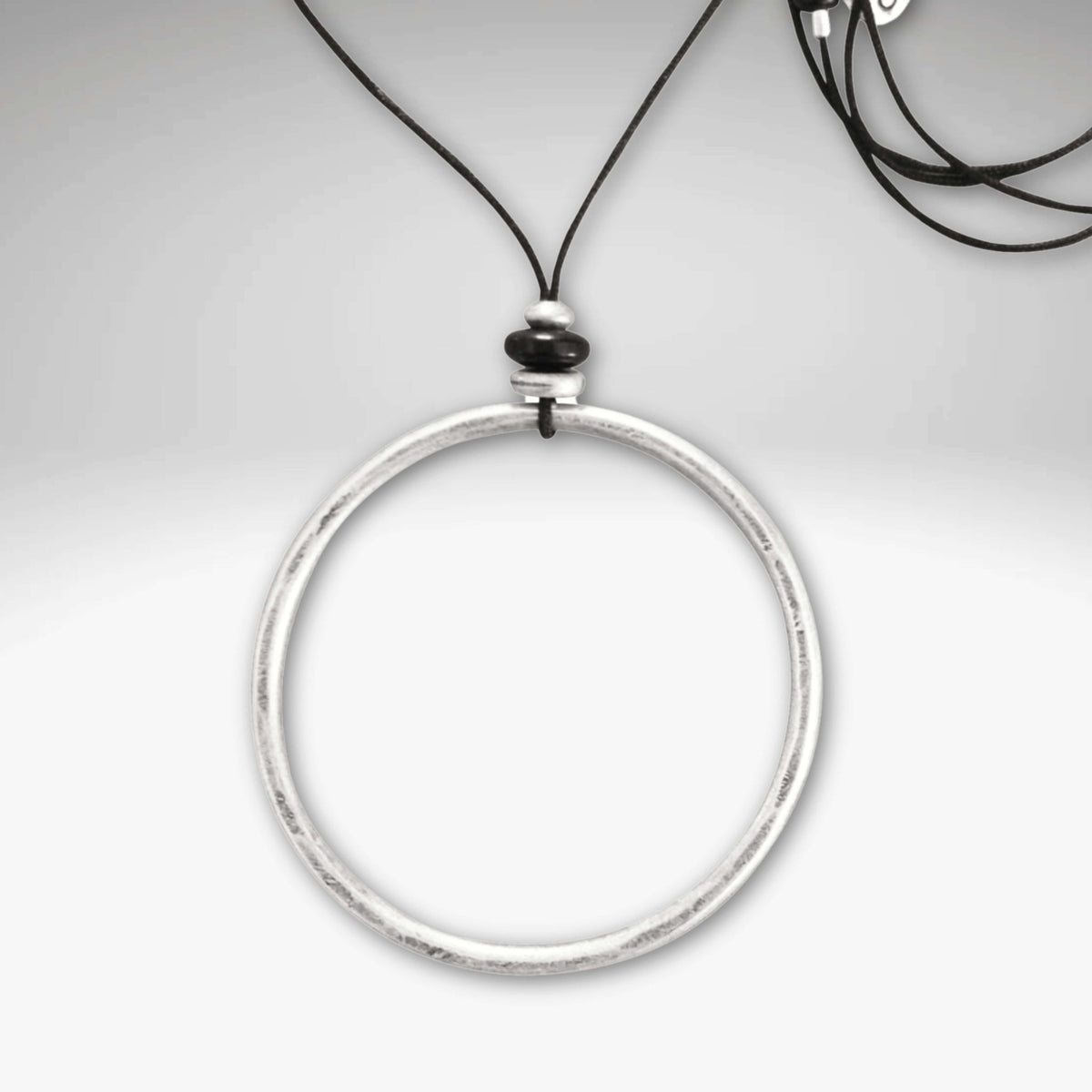 Hula Necklace featuring a 2" diameter raw brass circle hoop with asterling silver coating on a monofilament cord.