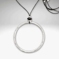 Hula Necklace featuring a 2" diameter raw brass circle hoop with asterling silver coating on a monofilament cord.