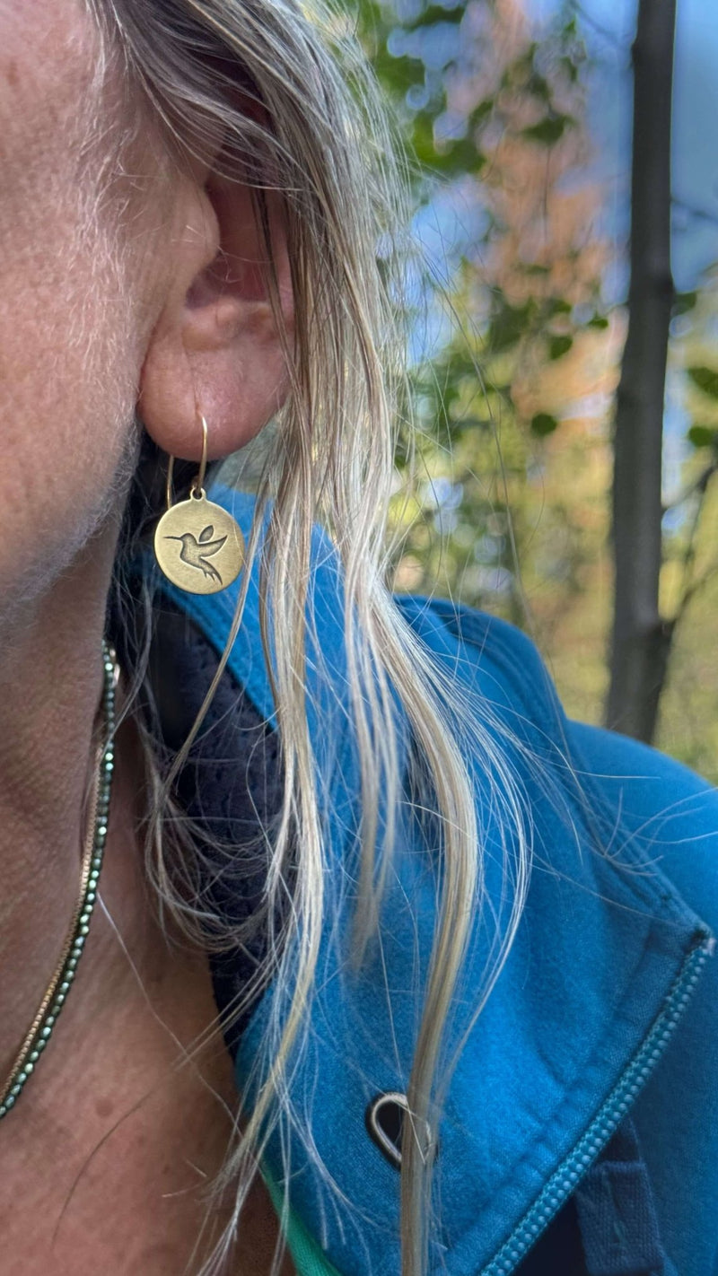 Hummingbird Earrings in antique brass finish worn by a model outdoors, perfect for nature lovers.