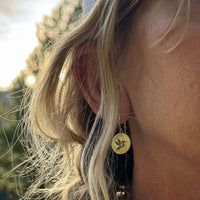 Hummingbird Earrings worn by a woman, featuring a hummingbird design on circular discs, showcasing their beauty.