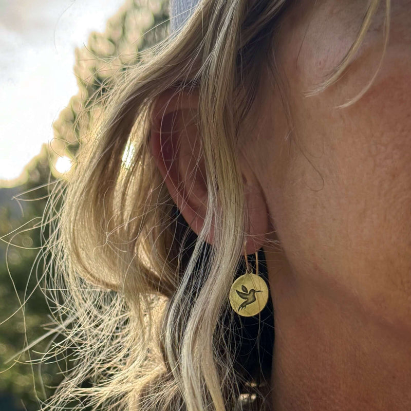 Hummingbird Earrings worn by a woman, featuring a hummingbird design on circular discs, showcasing their beauty.