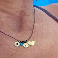 Initial Necklace featuring the initials A and L with a heart charm, personalized jewelry on a leather cord.