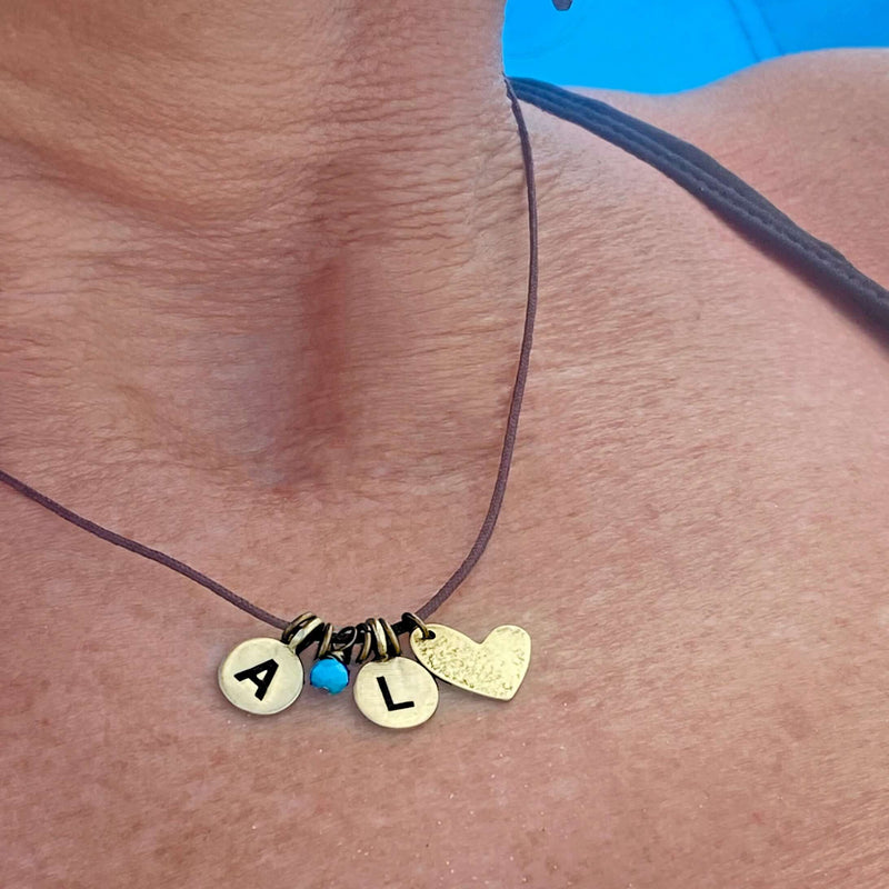 Initial Necklace featuring the initials A and L with a heart charm, personalized jewelry on a leather cord.