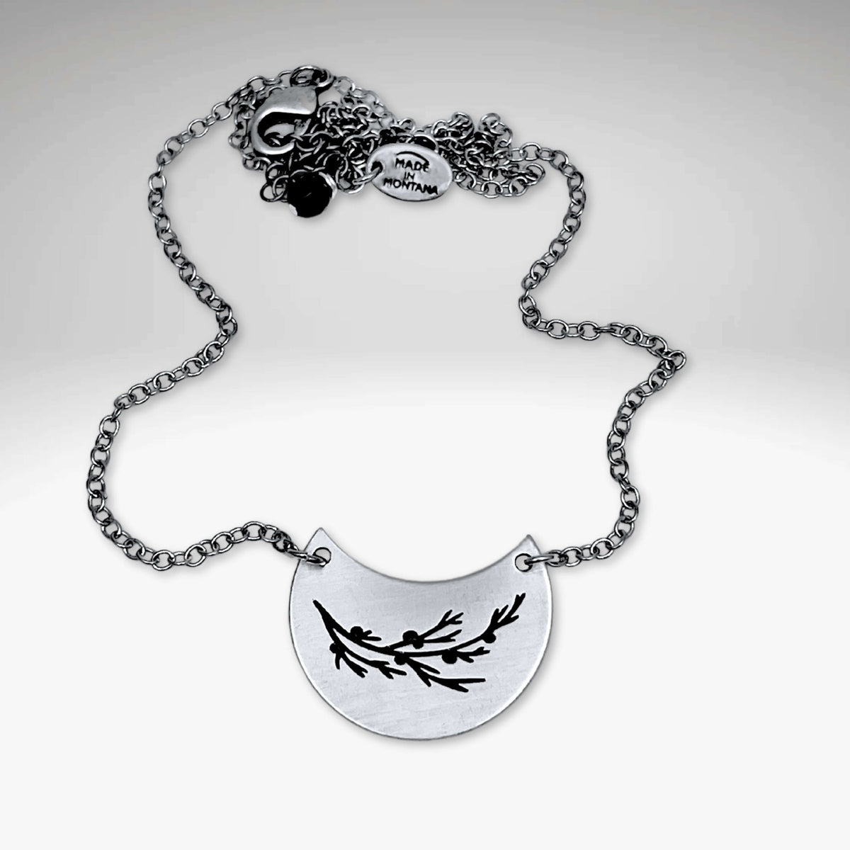 Juniper Necklace on a silver chain featuring a pendant with Juniper leaves and berries design.