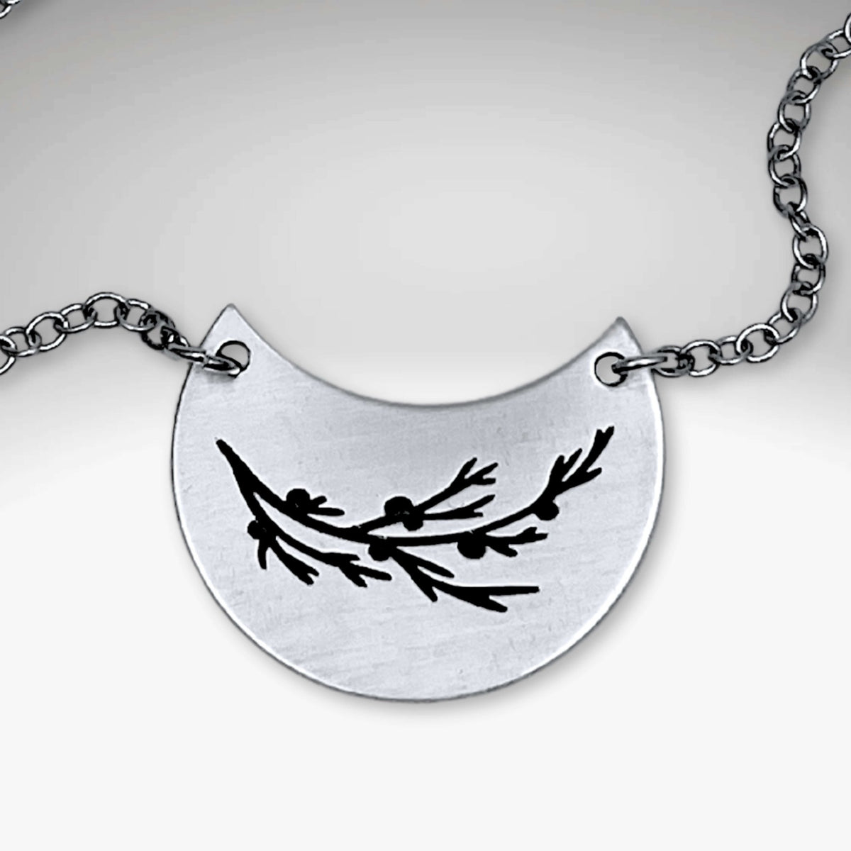 Juniper Necklace featuring a silver pendant with a Juniper sprig design on a rolo chain.