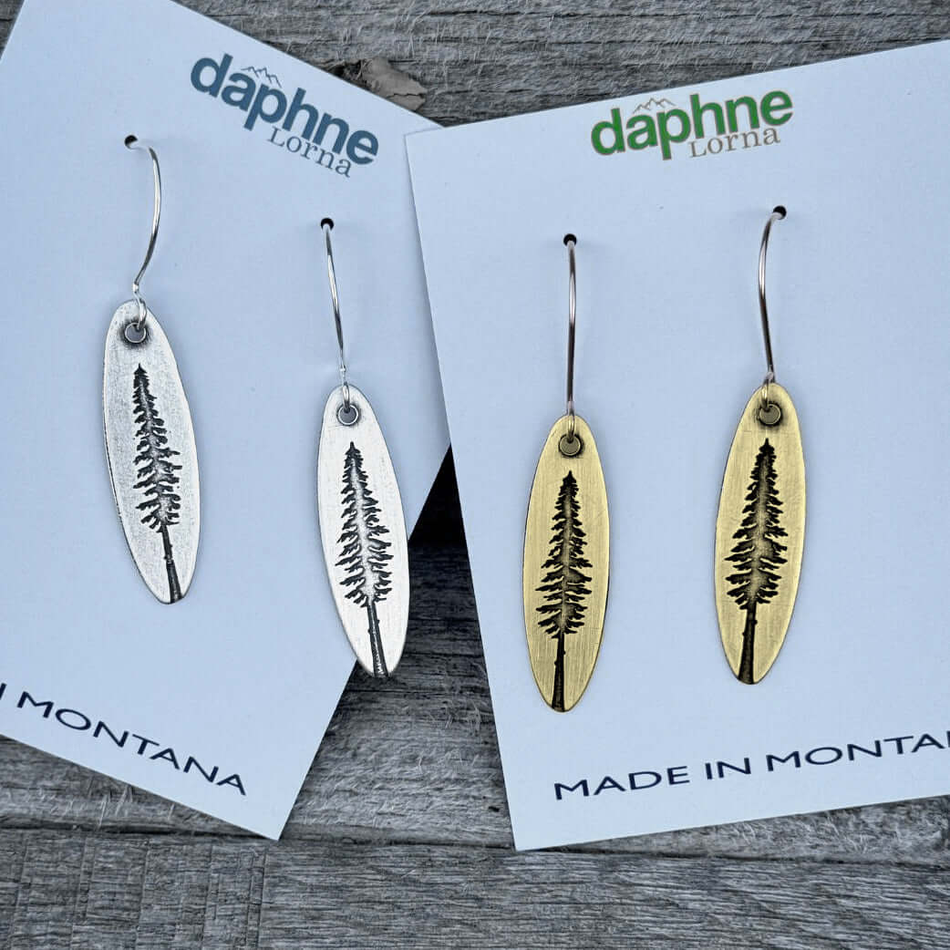 Larch Tree Earrings displayed in silver and antique brass on cards labeled 'Made in Montana'.