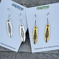 Larch Tree Earrings displayed in silver and antique brass on cards labeled 'Made in Montana'.