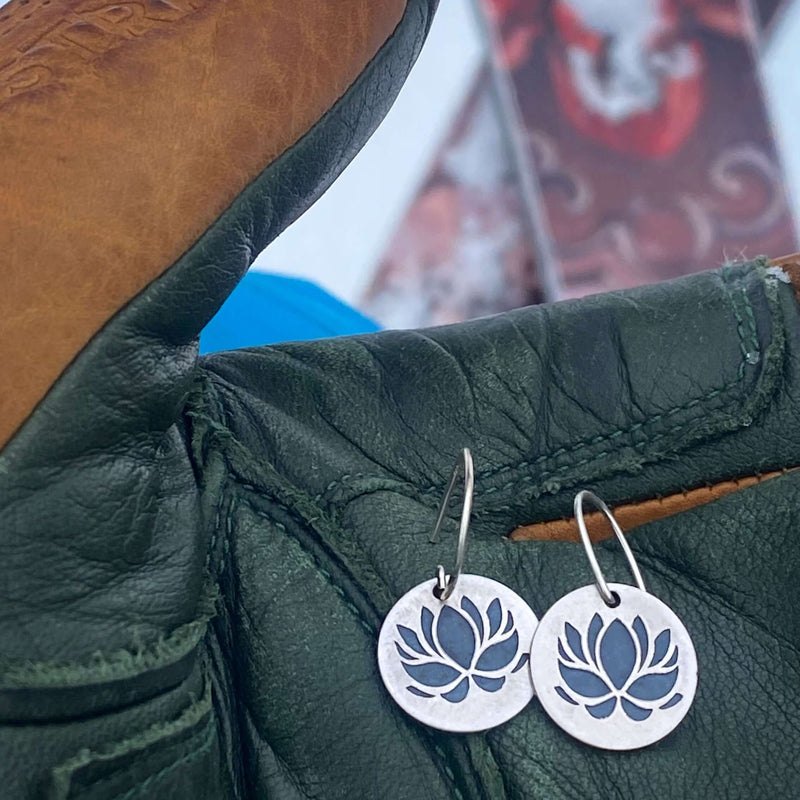 Lotus Flower Earrings displayed on a leather glove, showcasing their elegant lotus design and metallic finishes.