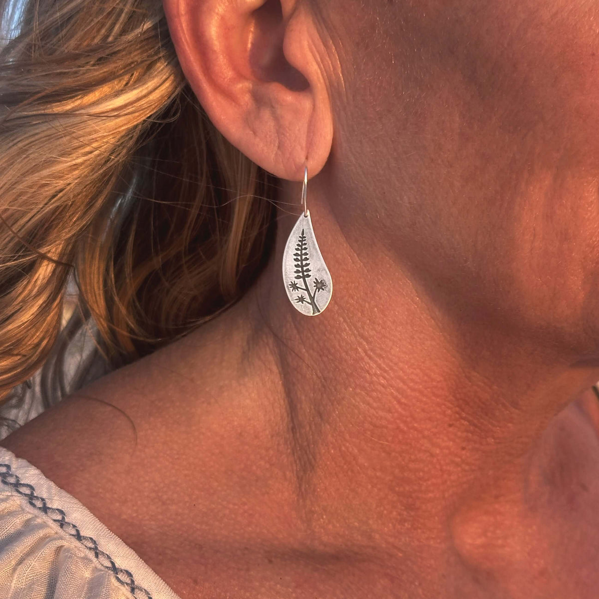 Lupine Flower Earrings showcased on a model's ear, highlighting their elegant teardrop design in matte silver finish.