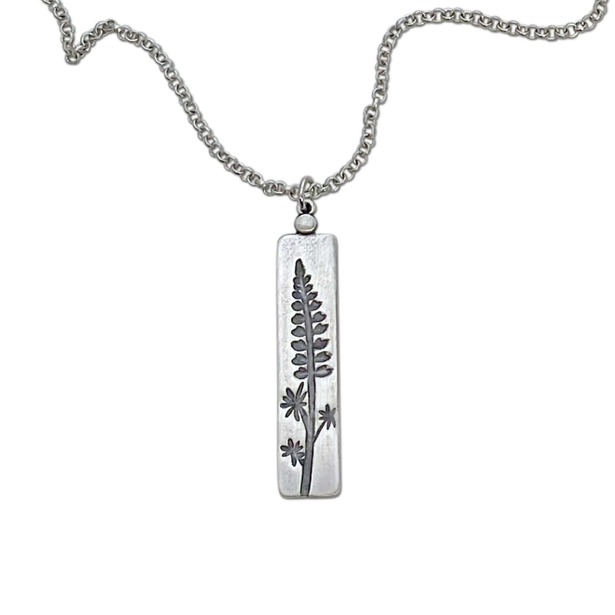 Lupine Necklace featuring a silver pendant with a wildflower design on an adjustable chain.
