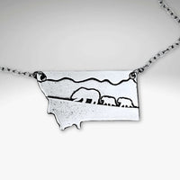 Mama and Cubs Necklace featuring an etched design of a grizzly bear and her cubs against a Montana backdrop.