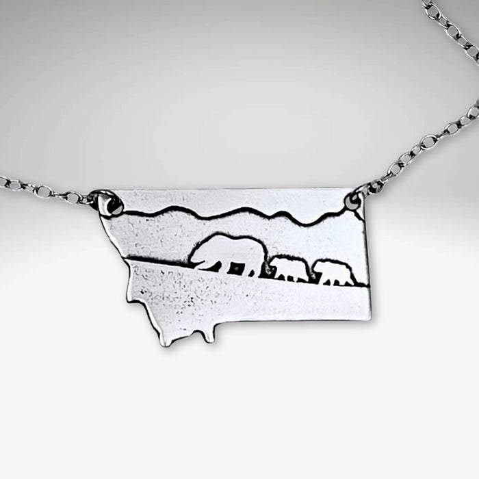 Mama and Cubs Necklace featuring an etched design of a grizzly bear and her cubs against a Montana backdrop.