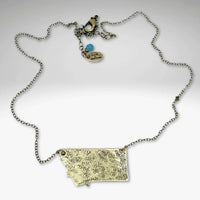 Montana Necklace on a light cable chain with textured Montana outline and charm, adjustable length up to 30 inches.