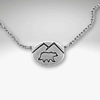 Mountain Bear Necklace in matte silver finish with bear and mountain design pendant.