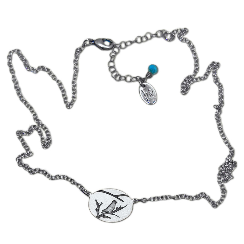 Mountain Bluebird Necklace featuring a delicate bluebird design on an oval pendant with adjustable chain.