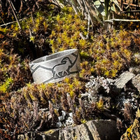 Mountain Goat Adjustable Ring displayed on a bed of moss and rocks, showcasing its unique design and natural elements.