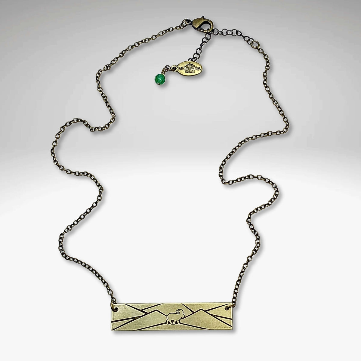 Mountain Goat Necklace on an antique brass chain with a mountain design, perfect for nature enthusiasts.