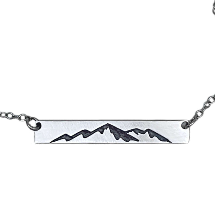 Mountainscape Necklace featuring a raw brass bar etched with a mountain silhouette on an adjustable cable chain.