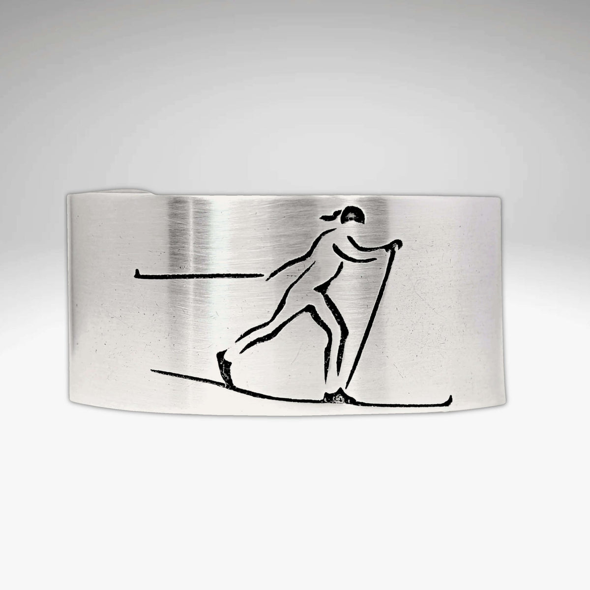 Nordic Run Cuff Bracelet with an etched image of a Nordic skier skiing in snow, perfect for outdoor adventure lovers.