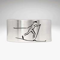 Nordic Run Cuff Bracelet with an etched image of a Nordic skier skiing in snow, perfect for outdoor adventure lovers.