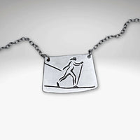 Nordic Run Necklace featuring a unique etching of a skier on a simple cable chain, perfect for winter travel lovers.