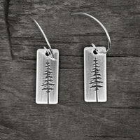 P Pine Tree Earrings featuring a Ponderosa Pine Tree design with sterling silver earwires on a wooden background.