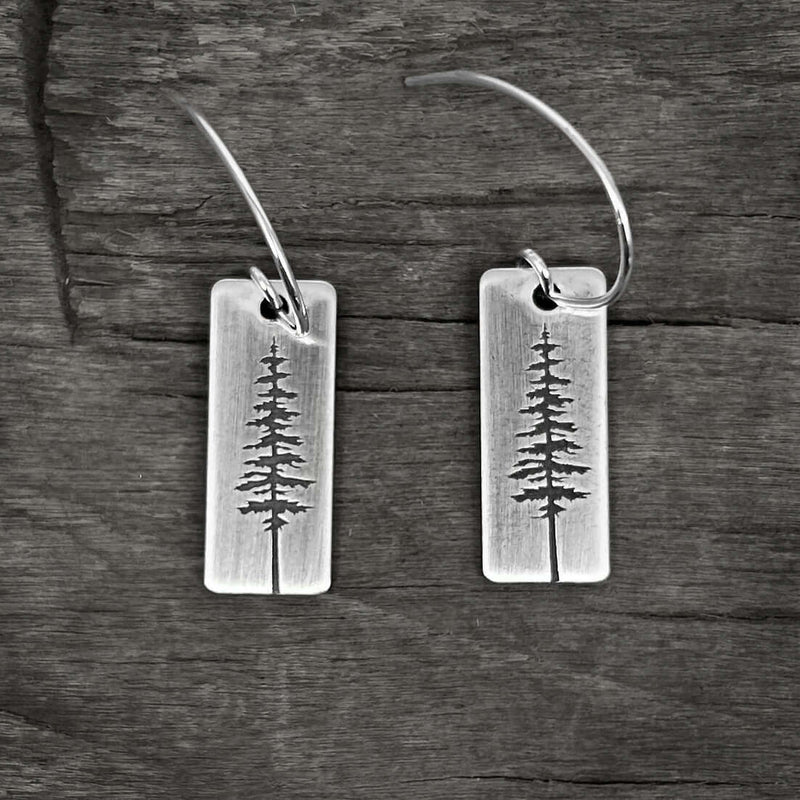 P Pine Tree Earrings featuring a Ponderosa Pine Tree design with sterling silver earwires on a wooden background.