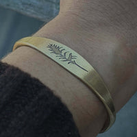 Paintbrush Signet Cuff shown in antique brass on wrist, featuring intricate design, handmade in Montana.