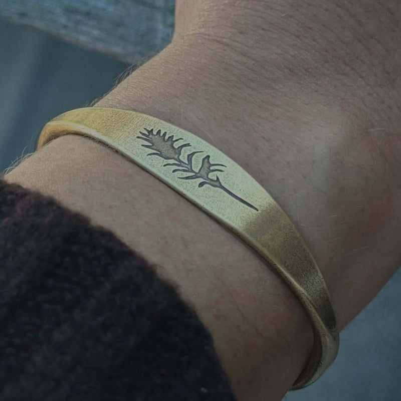 Paintbrush Signet Cuff shown in antique brass on wrist, featuring intricate design, handmade in Montana.