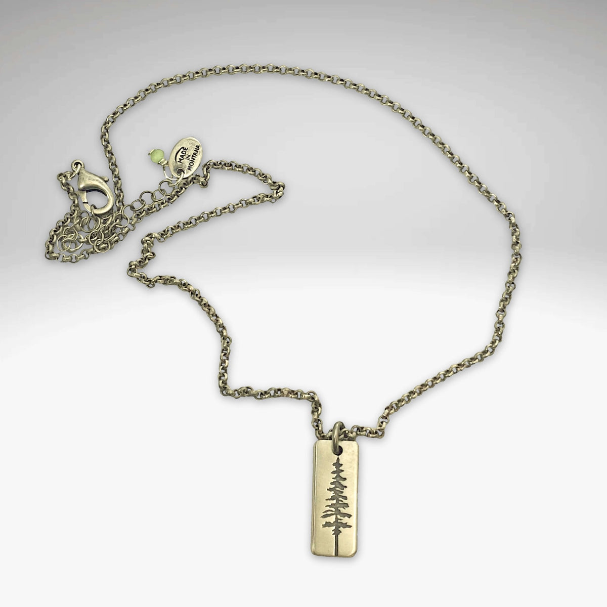 Pine Tree Necklace featuring a Ponderosa Pine pendant on a chain, available in Matte Silver and Antique Brass finishes.
