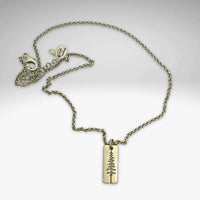 Pine Tree Necklace featuring a Ponderosa Pine pendant on a chain, available in Matte Silver and Antique Brass finishes.